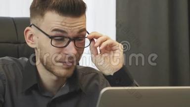 商人在网上看新闻，特写。男人的肖像戴上眼镜，看着笔记本电脑屏幕。男职工